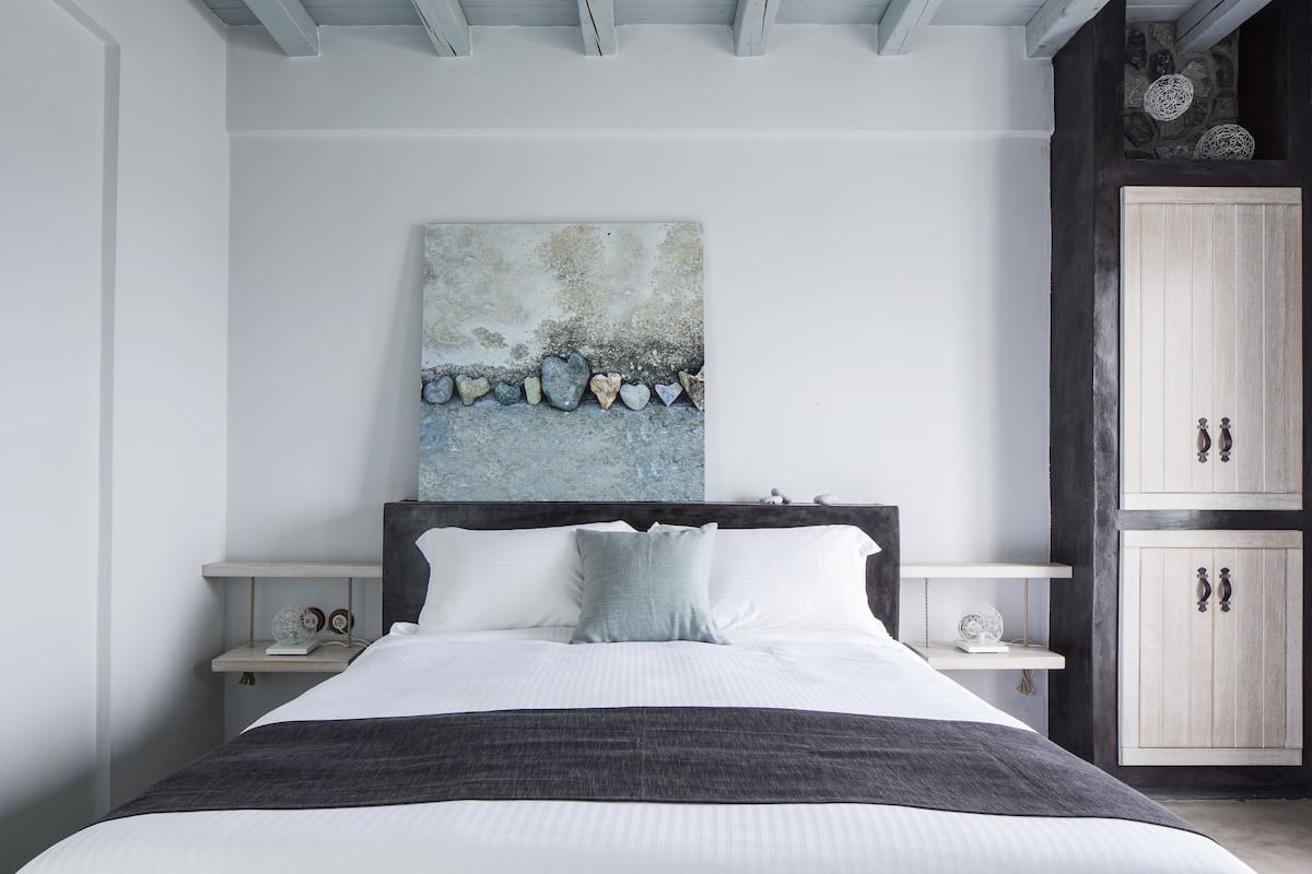 A bedroom with a large bed, a painting on the wall, and wooden cabinets.