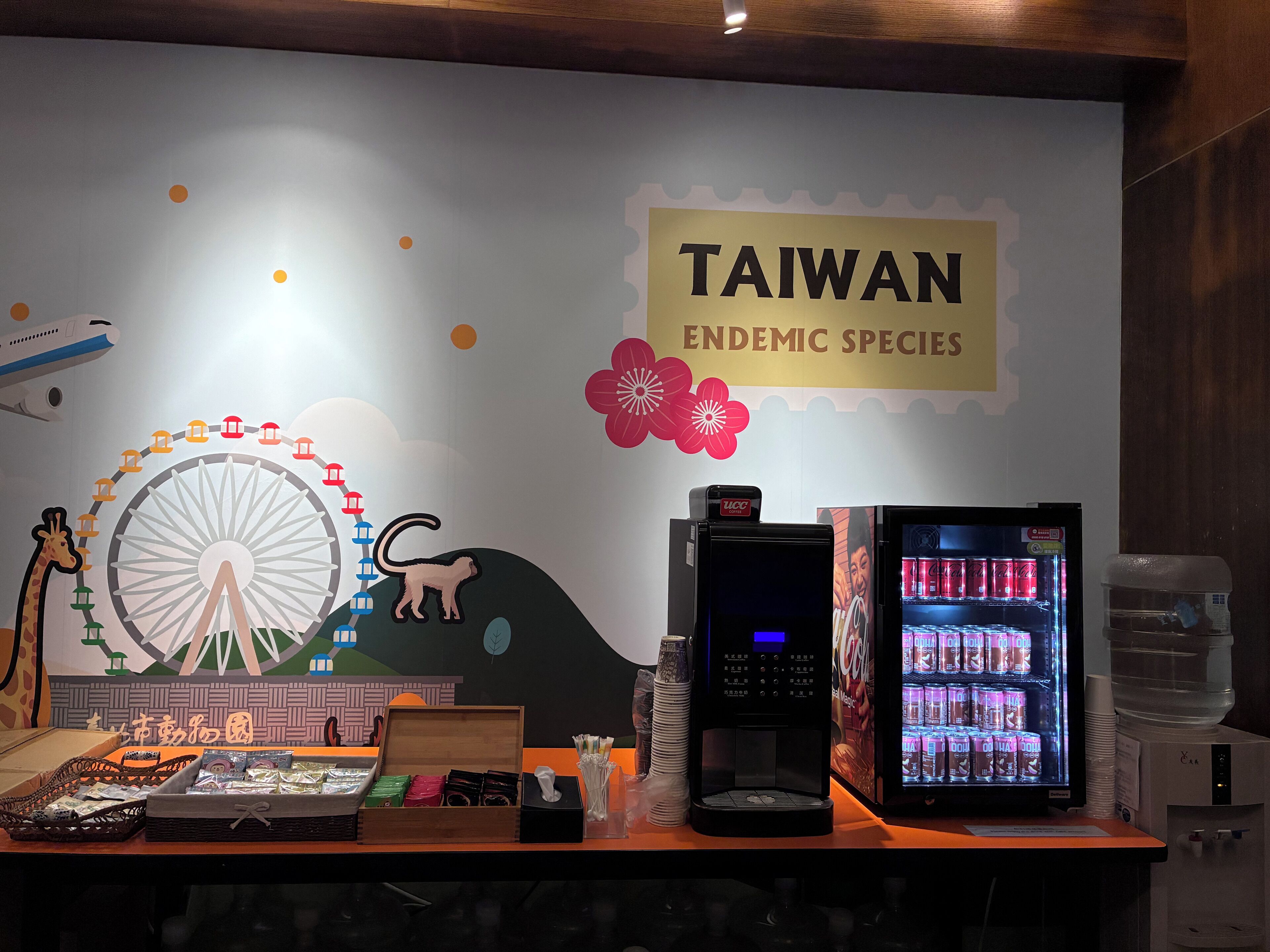 A vending machine, a coffee machine, and a water dispenser on a counter with a sign reading "Taiwan Endemic Species".