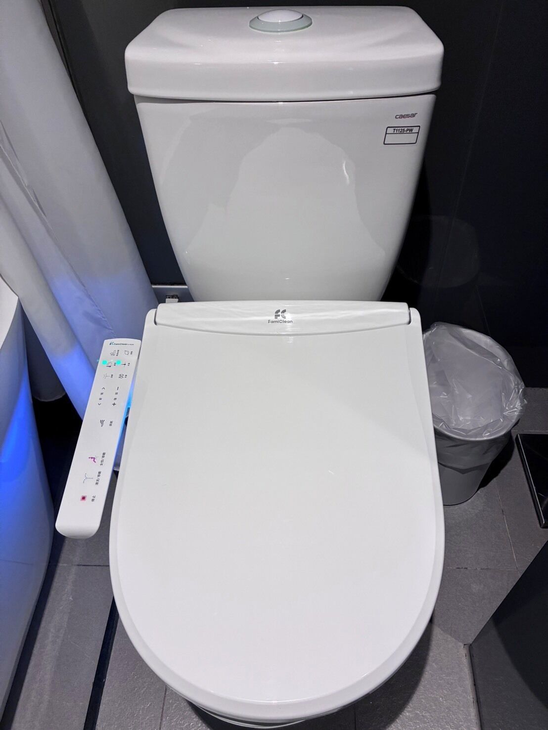 A modern toilet with a control panel and a bidet attachment.