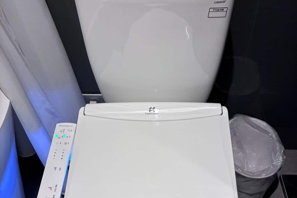 A modern toilet with a control panel and a bidet attachment.
