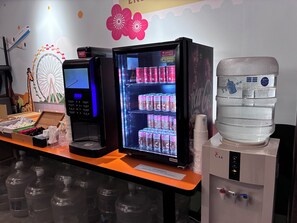 A vending machine with a selection of drinks, a water dispenser, and a small kiosk with a computer. - Newful Hotel (Taipei)