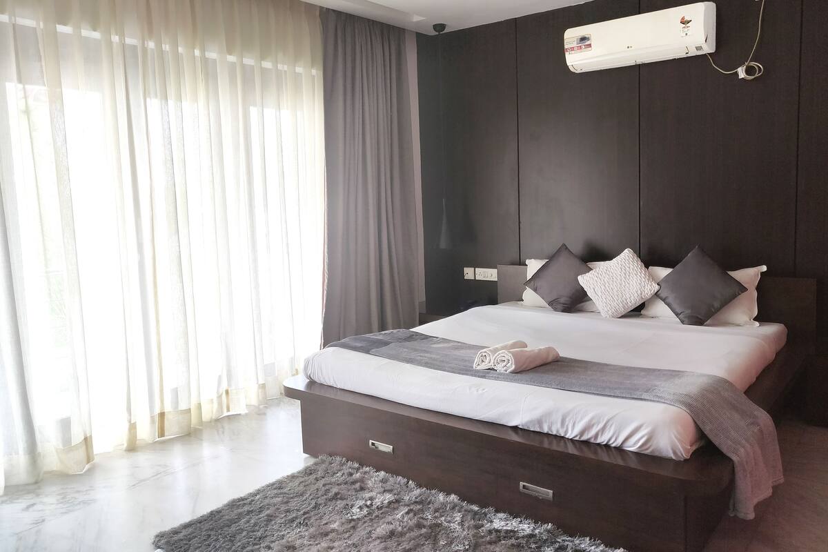 Un dormitorio moderno con una cama grande, un ventilador de techo y un equipo de aire acondicionado.