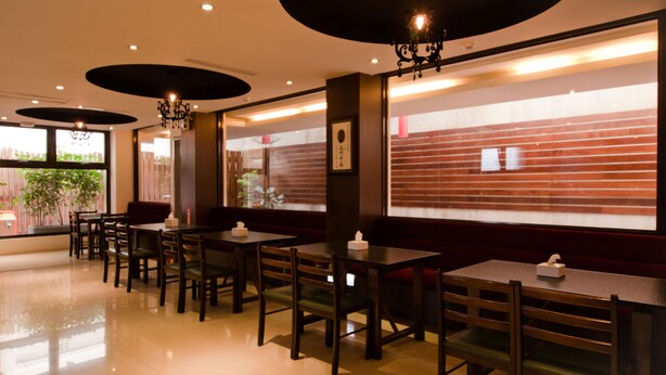 Ein Restaurant mit Holztischen und -stühlen, großen Fenstern und einem modernen Innendesign.