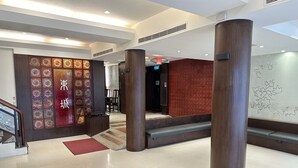 Eine moderne Lobby mit einer roten Wand mit Muster, einer Treppe und einer großen Säule.