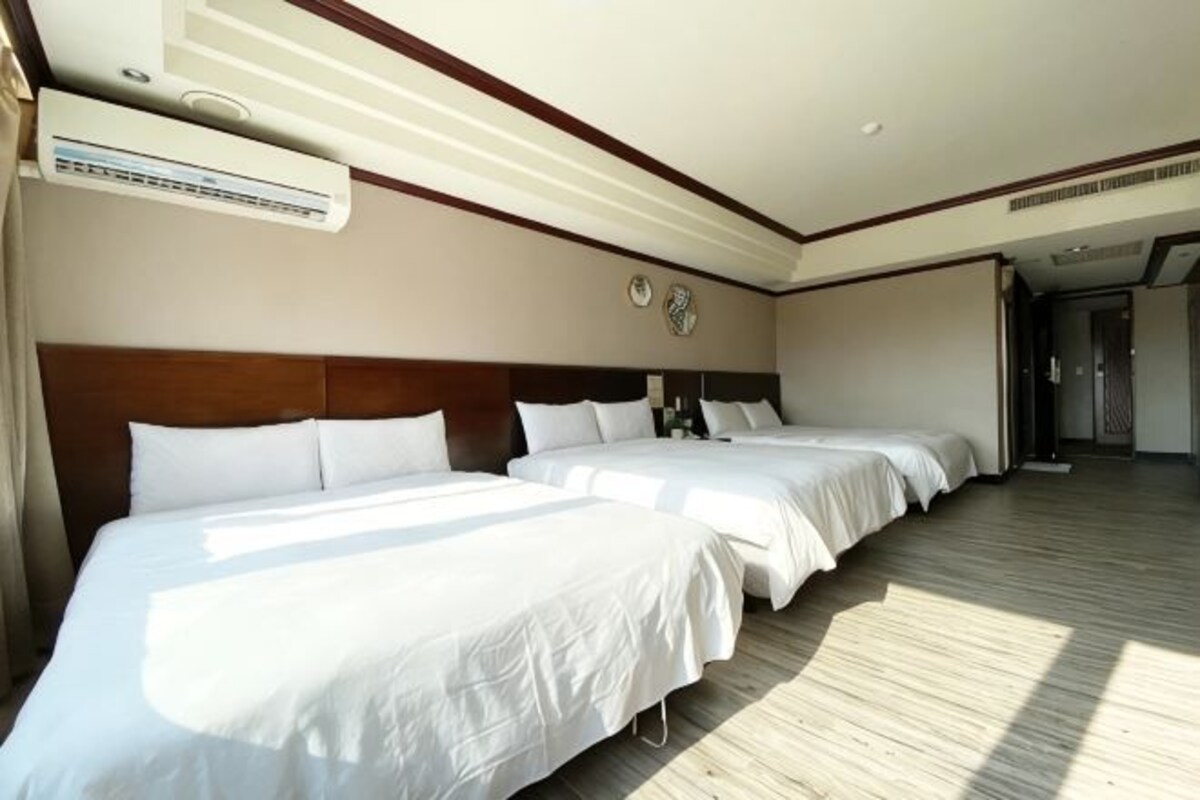 Ein Hotelzimmer mit zwei Betten, Holzboden und einem großen Fenster.