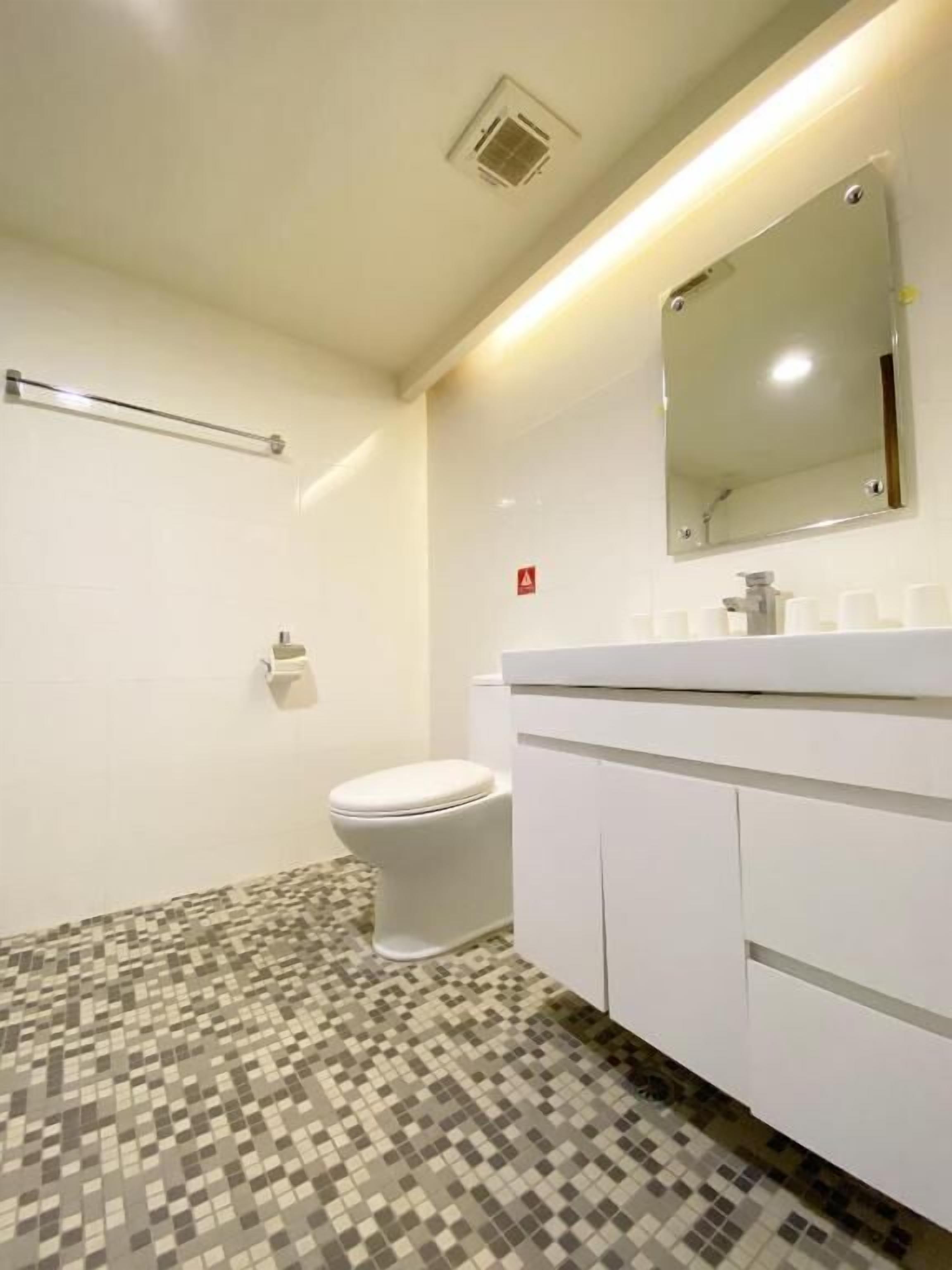 A bathroom with a toilet, a sink with a mirror, and a patterned floor.