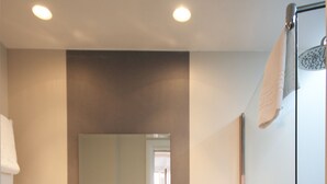 Un baño moderno con un espejo grande, un lavabo y una ducha.