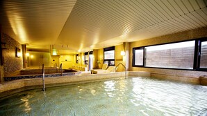 Una piscina interior con paredes de azulejos y techo de listones de madera.