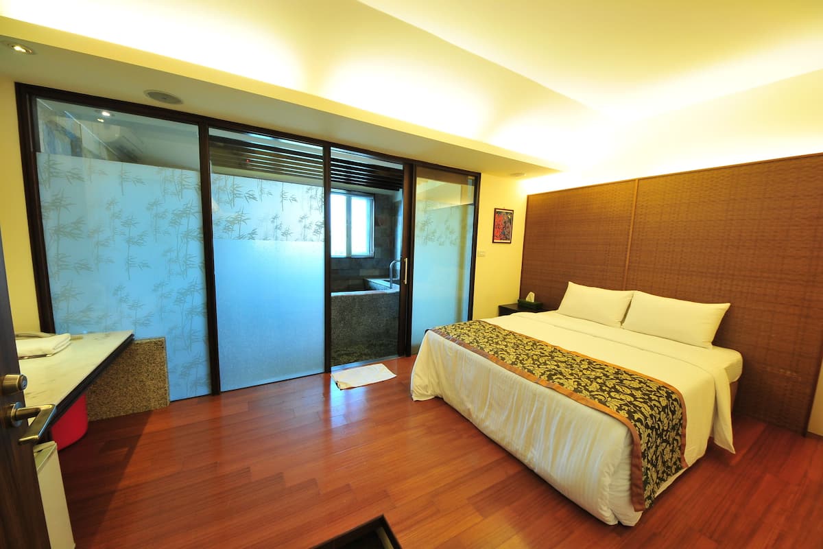 A hotel room with a bed, a desk, and a sliding door with frosted glass.