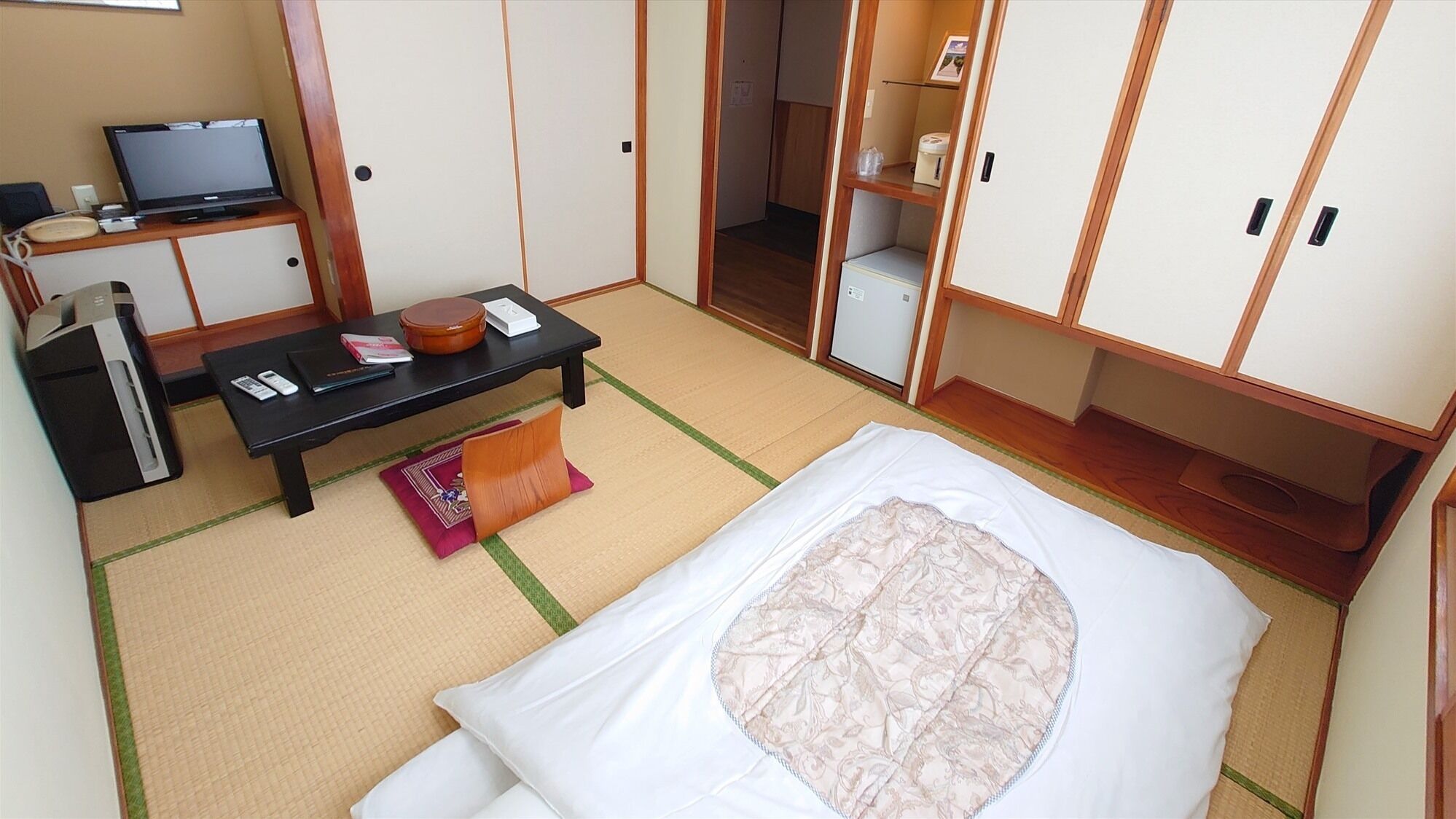 A room with a bed, a desk, a television, and a wardrobe.