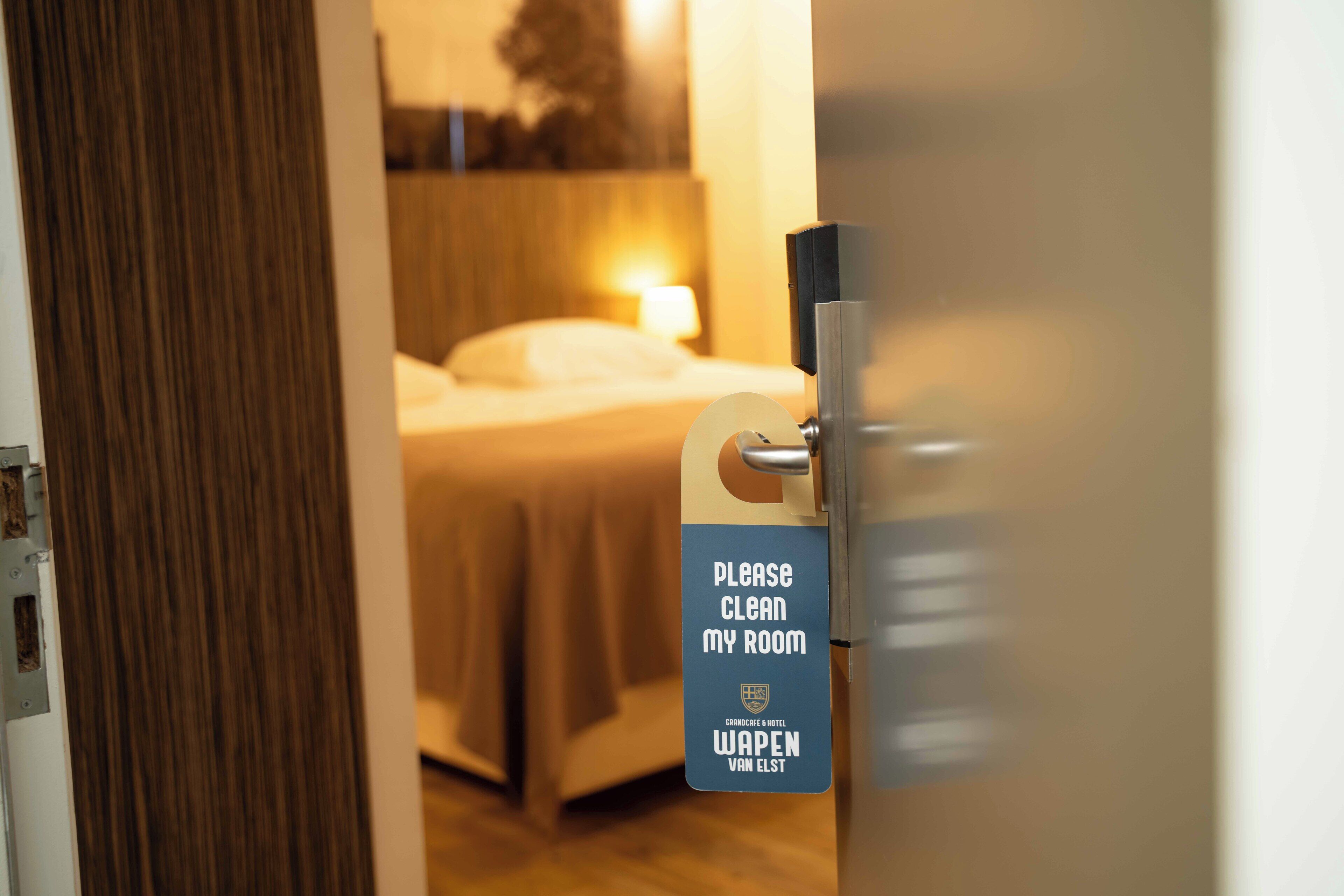 A hotel room door with a sign requesting guests to clean their room.