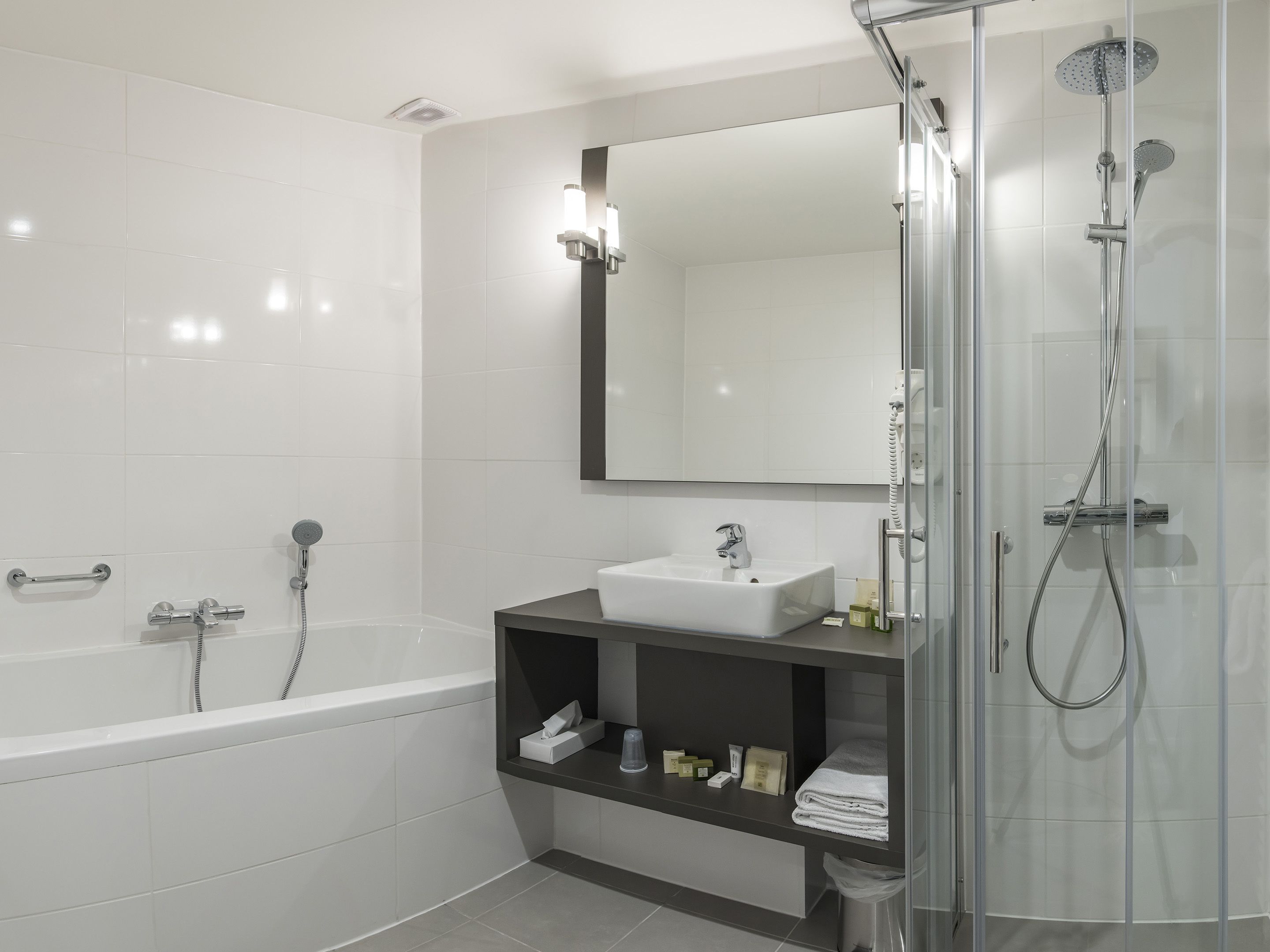 A modern bathroom with a bathtub, a sink, a mirror, and a shower.