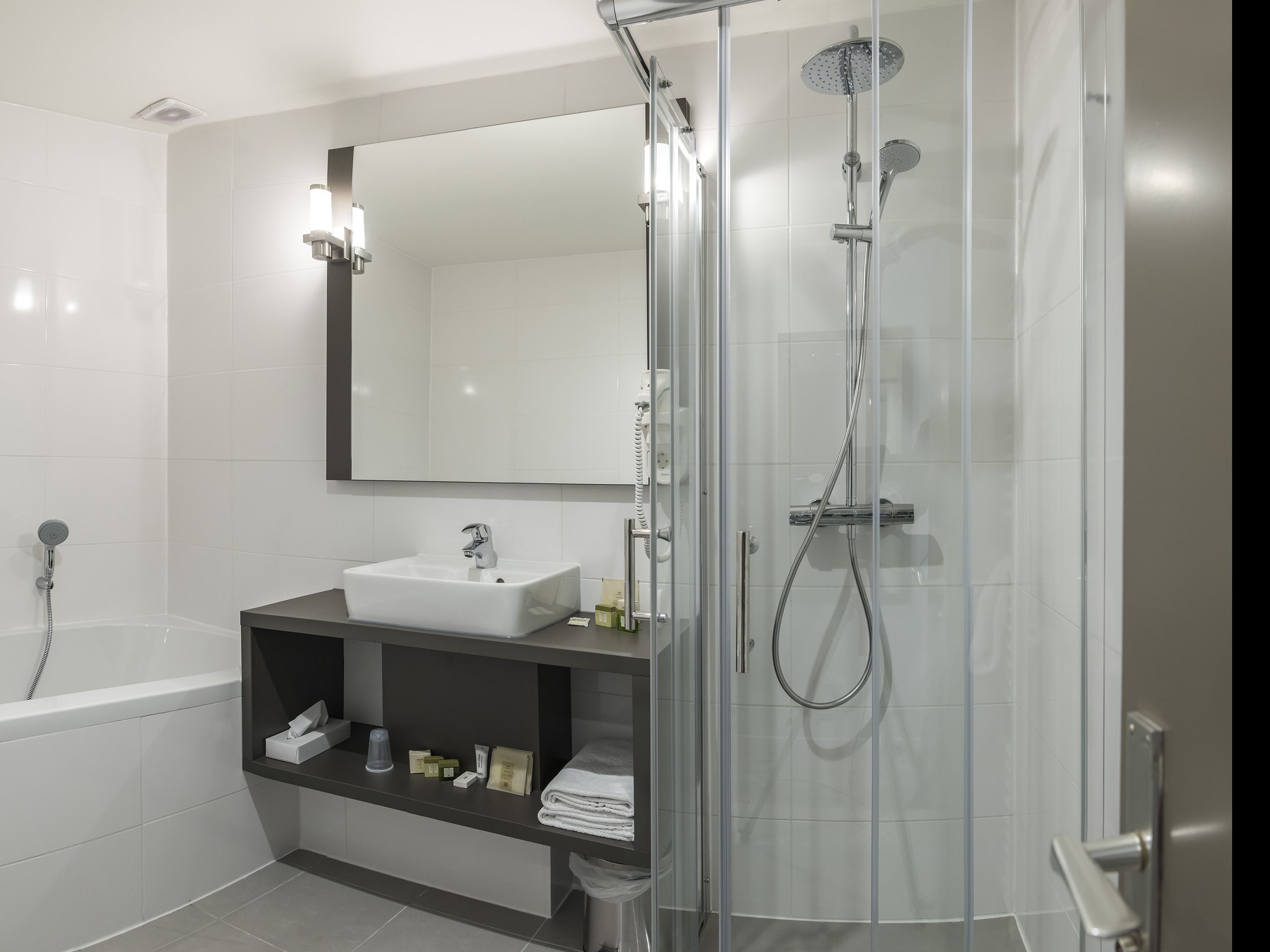 Une salle de bain moderne dotée d’une douche à parois de verre, d’une baignoire sur pieds et d’un meuble-lavabo avec un miroir au-dessus du lavabo.