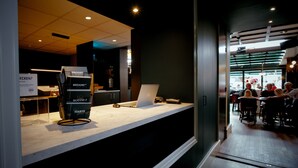 A reception desk with a laptop, a stack of cards, and a sign with text. - Het Wapen van Elst (Elst)