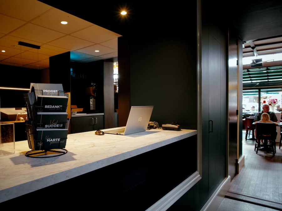 Una reception con un computer portatile, una pila di biglietti e un cartello con del testo.
