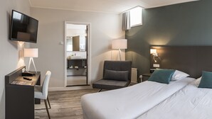 A modern hotel room with a large bed, a desk with a chair, a television, and a bathroom visible through an open door. - Het Wapen van Elst (Elst)