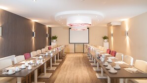A conference room with a long table, chairs, a projector screen, and a modern ceiling design. - Het Wapen van Elst (Elst)