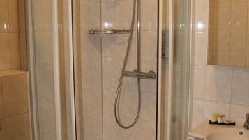 A corner shower with a glass door, a toilet, and a sink with a mirror above it.