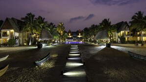 A beachfront resort with thatched-roof buildings, a wooden walkway, and boats. - Maalu Maalu Resort & Spa (Pasikuda)