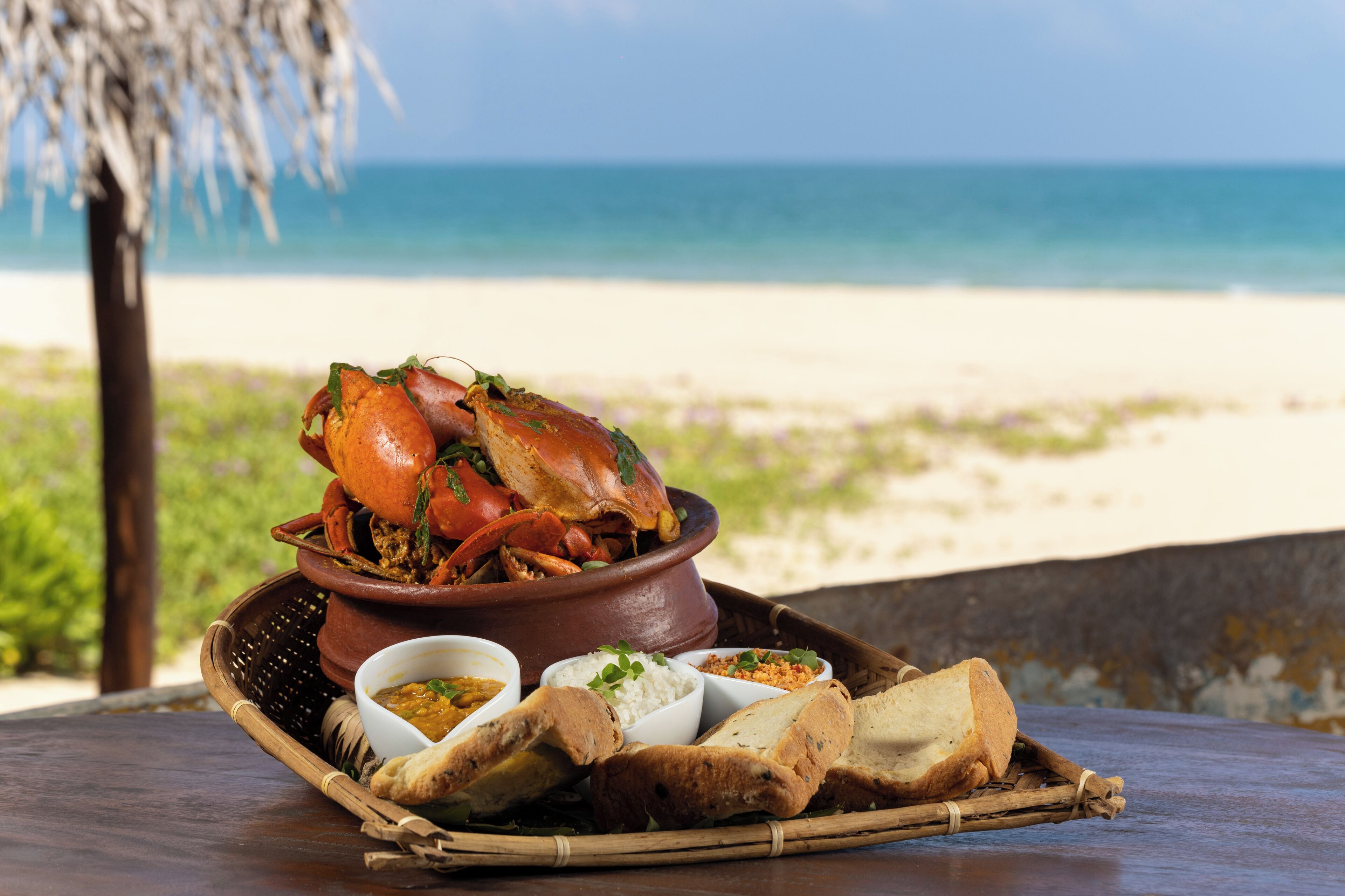 A meal of crab and bread on a table with a view of the beach and ocean.