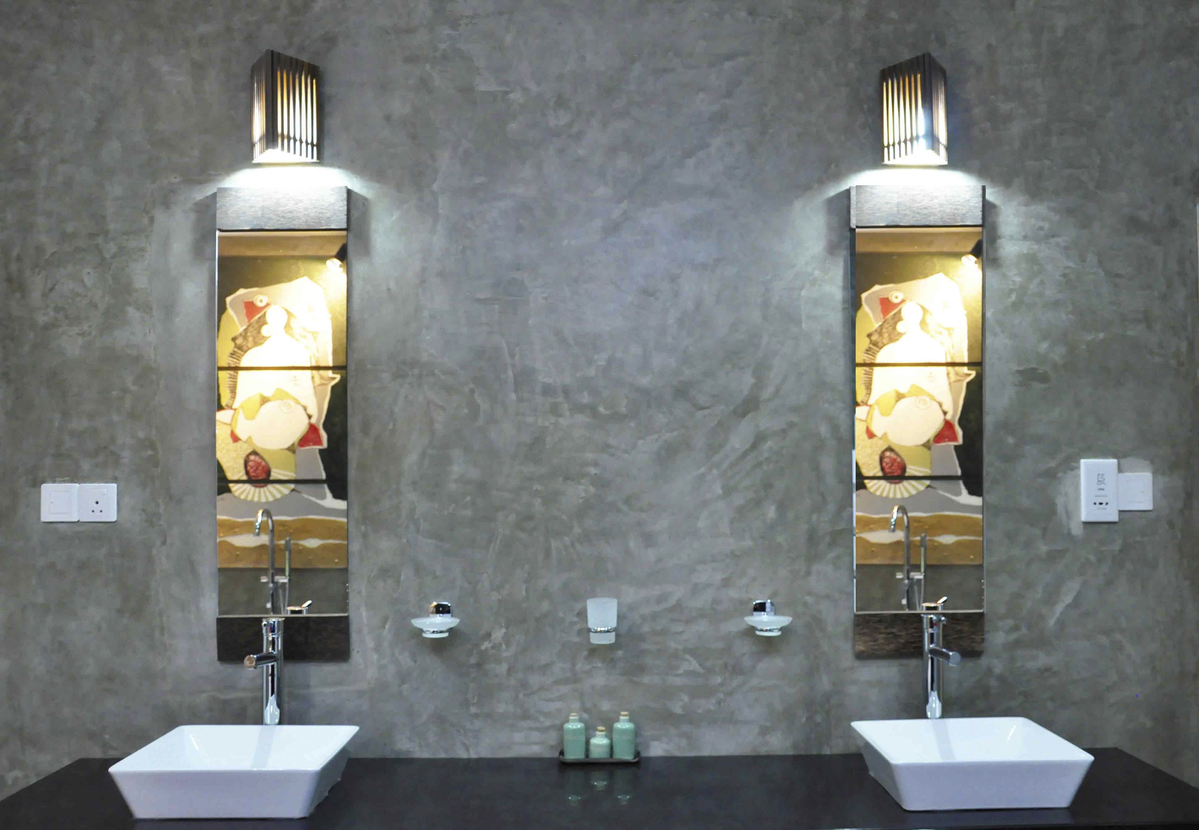 Une salle de bain avec deux lavabos, chacun étant équipé d’un miroir et d’un luminaire au-dessus. On trouve trois petits flacons sur le comptoir.