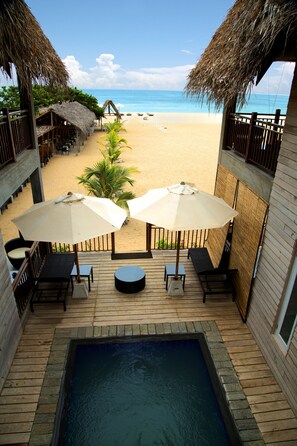Zona de piscina con vistas a la playa, con sillones de descanso y sombrillas.