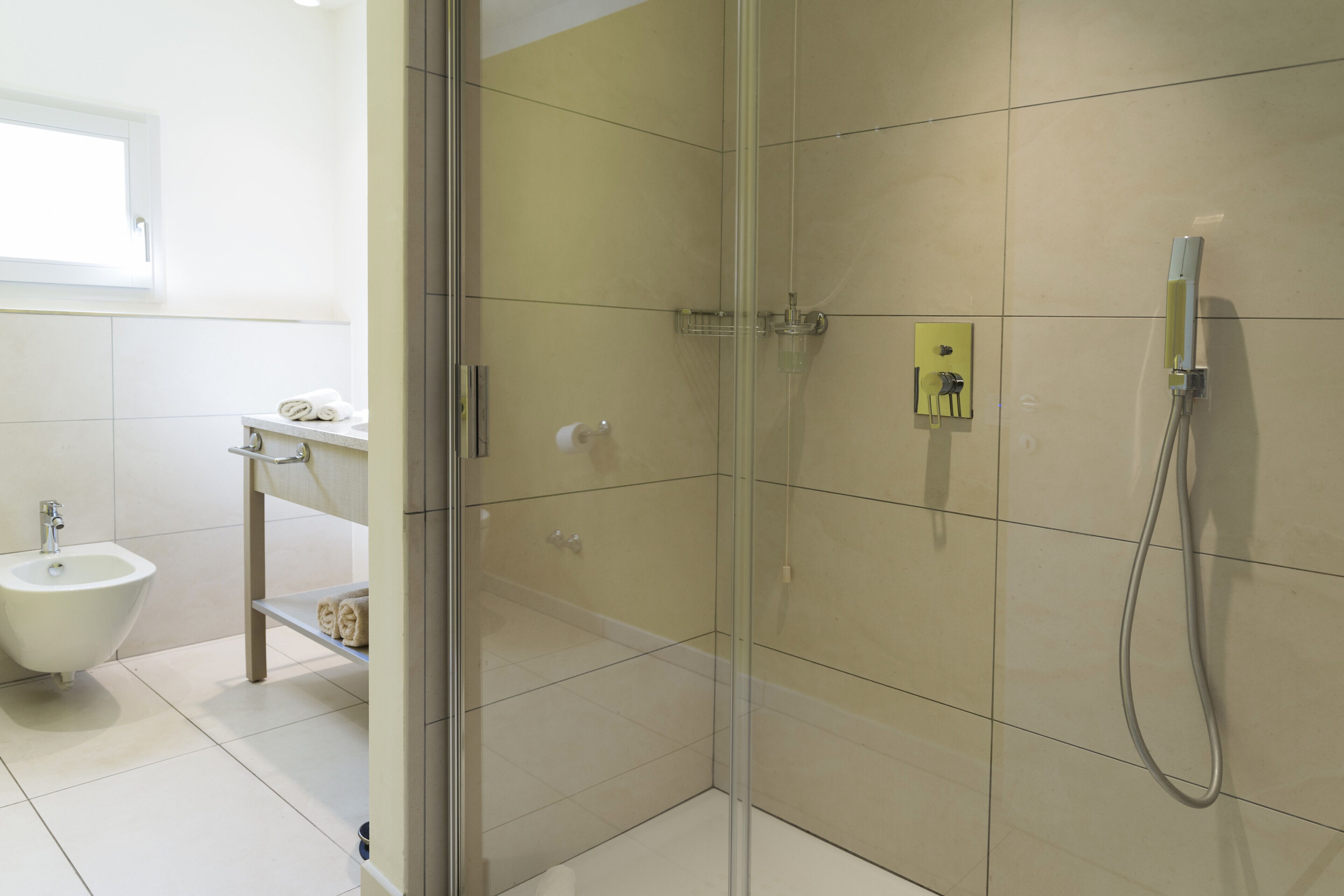 Une salle de bain moderne avec une douche à parois de verre, un bidet et un lavabo blanc.