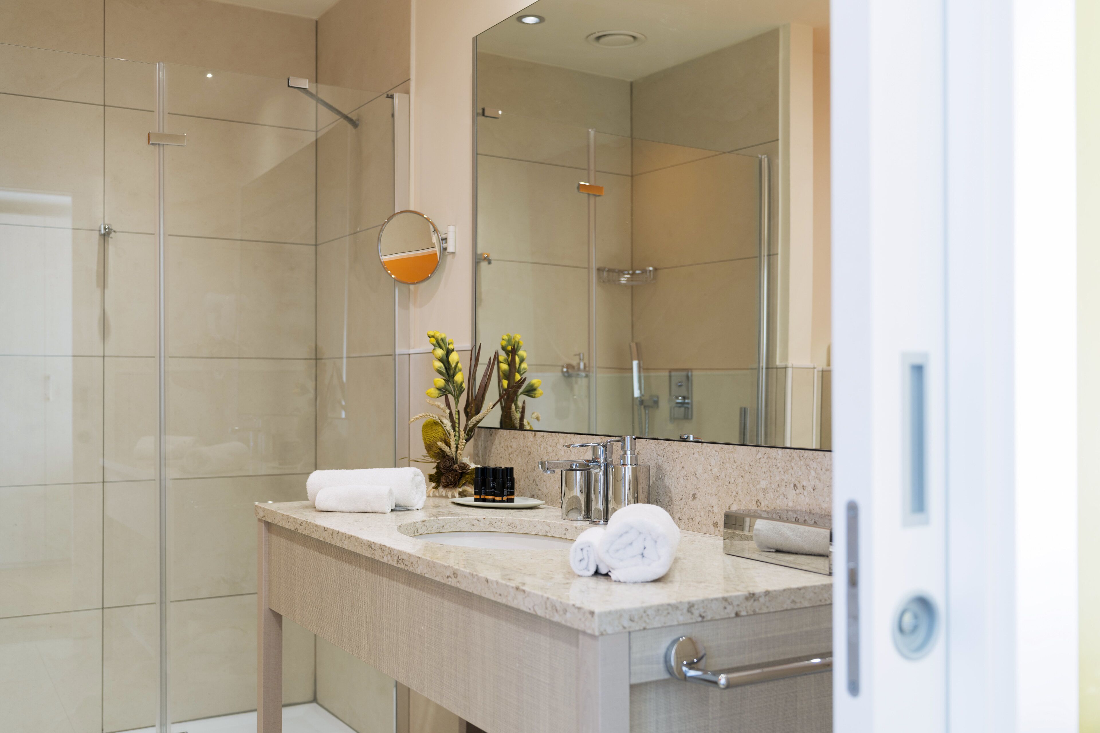 Un baño moderno con cabina de ducha de vidrio, un espejo grande y encimera de granito.