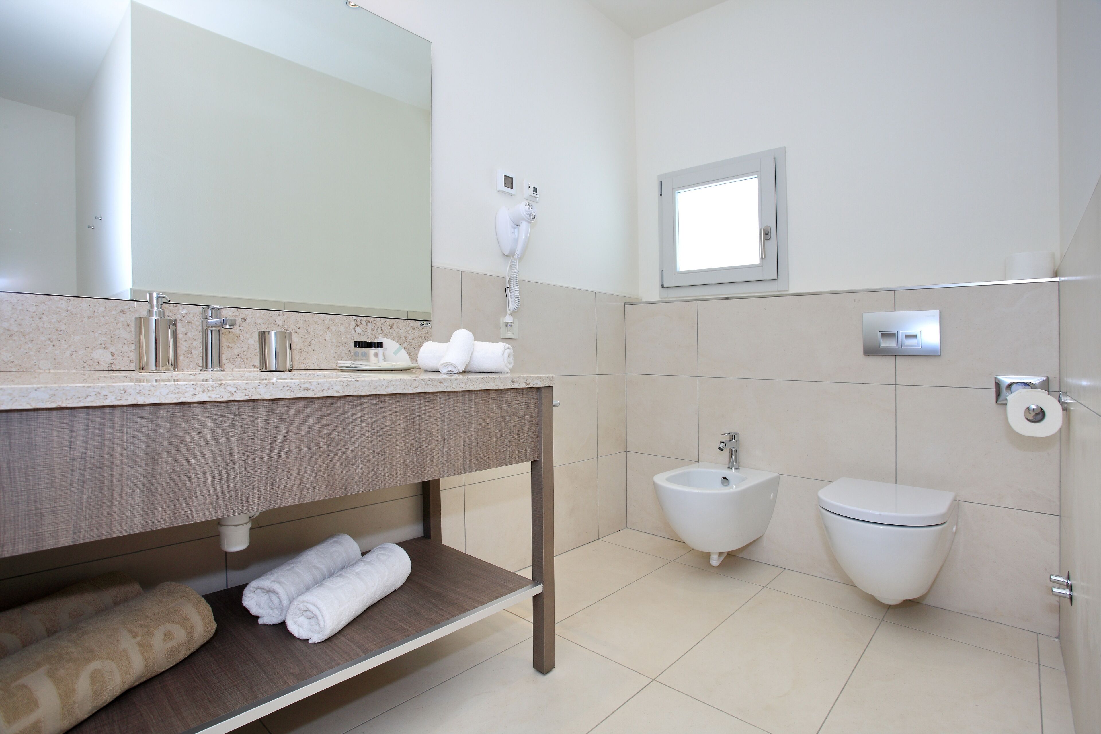 A modern bathroom with a vanity, towel rack, bidet, and toilet.