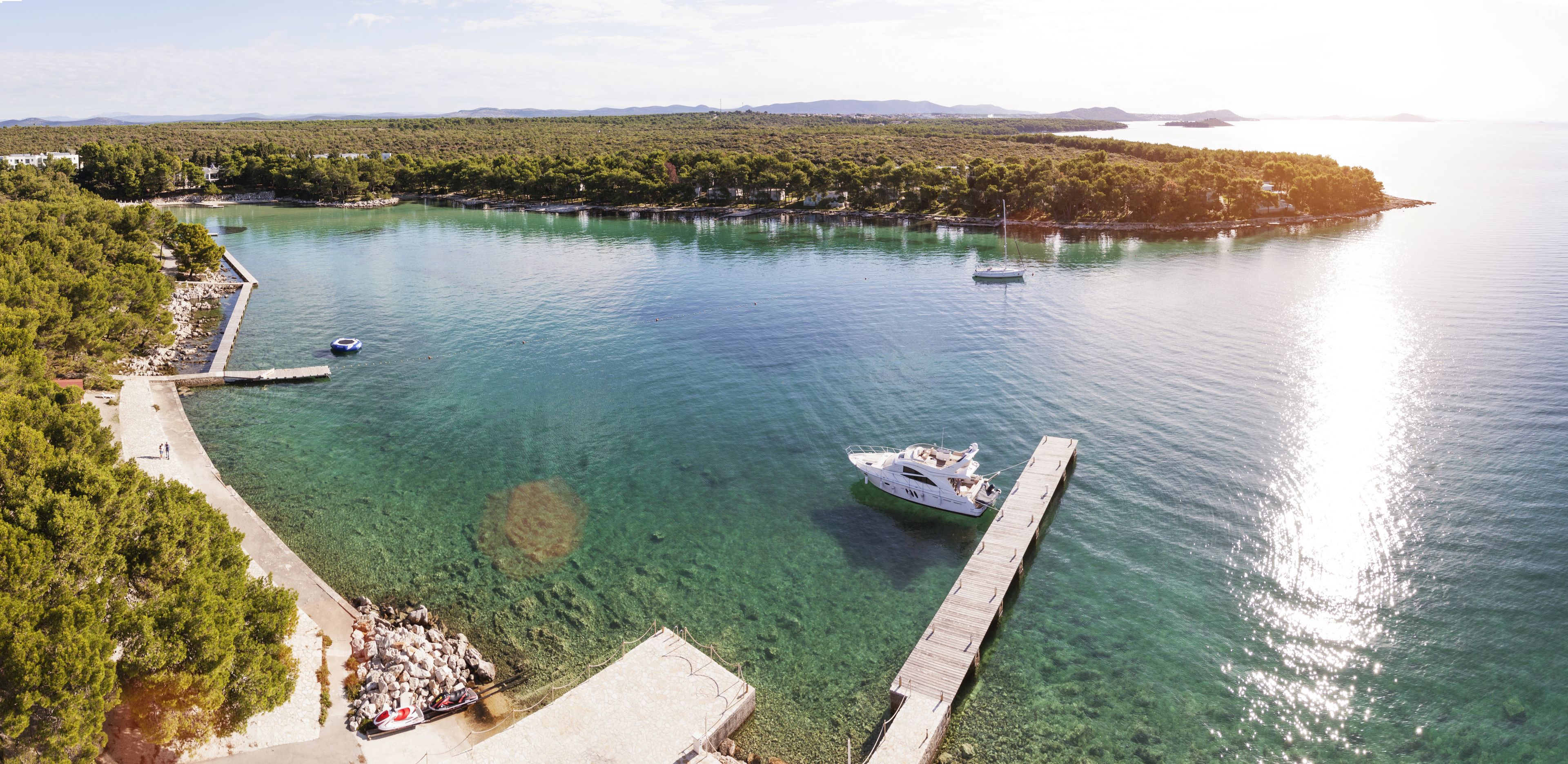 A coastal area with clear turquoise water, a pier, and a boat docked at the pier.