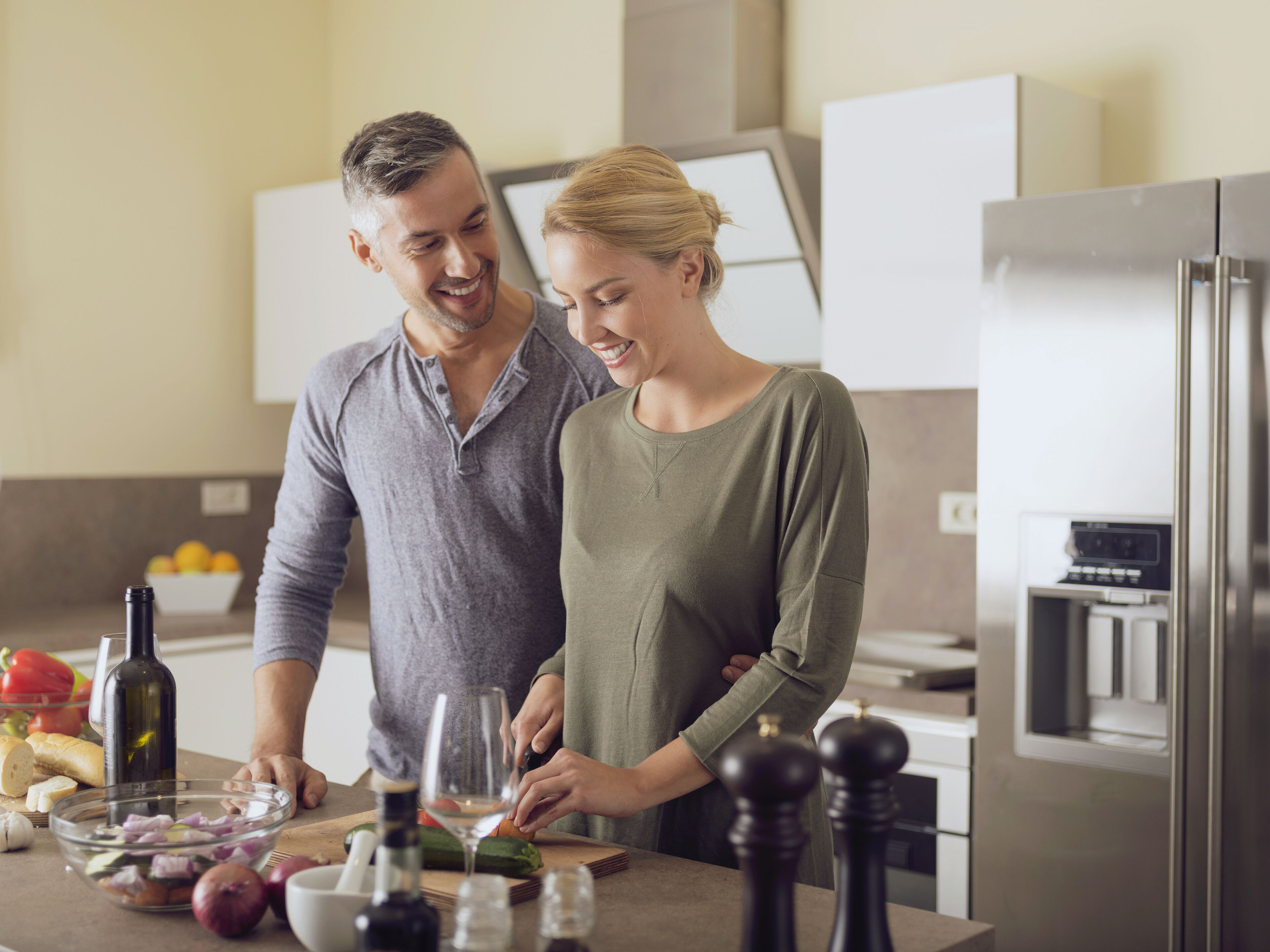 Una cocina moderna con un refrigerador de acero inoxidable, una encimera de madera y un tazón con ingredientes.