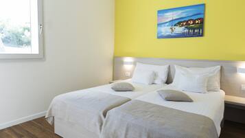A double bed with two pillows, a bedside table, and a painting on the wall.