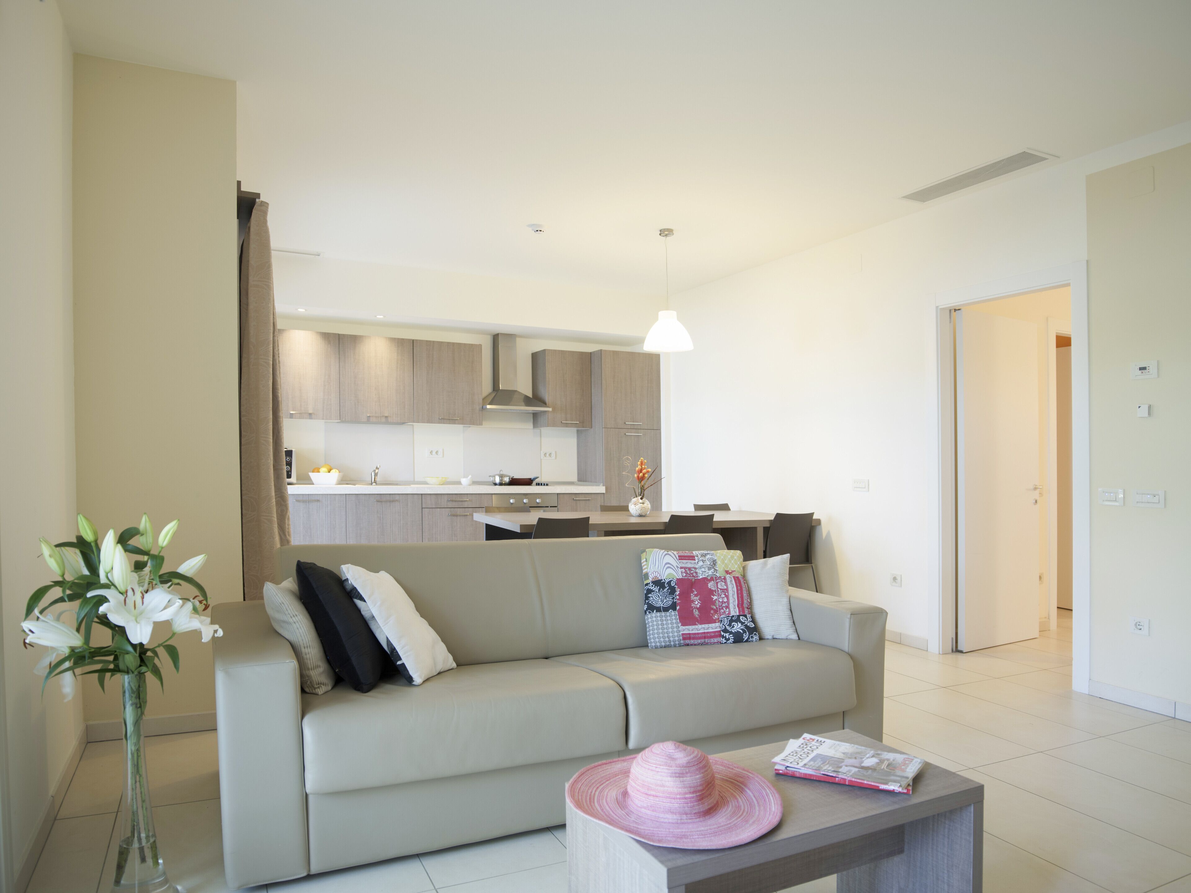 A modern living room with a sofa, a coffee table, and a vase of flowers.