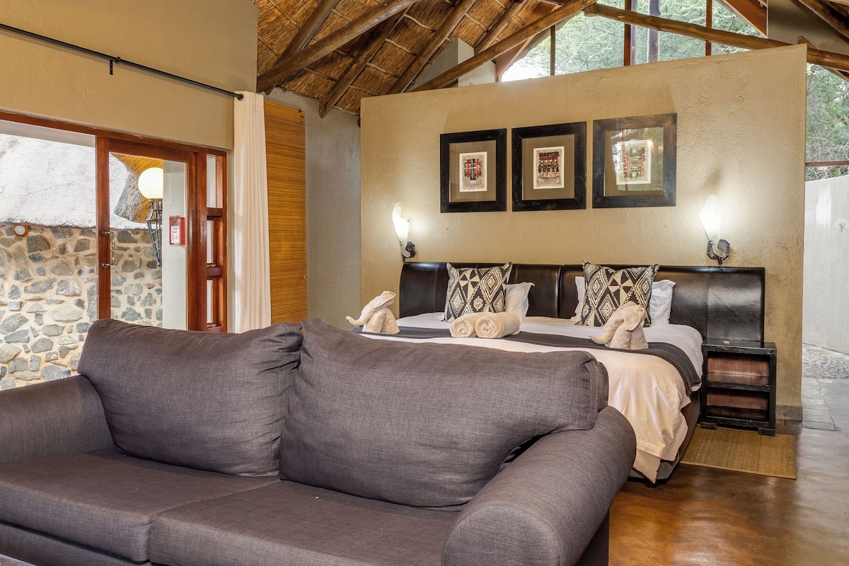 A bedroom with a bed, two wall-mounted lamps, and a stone wall.