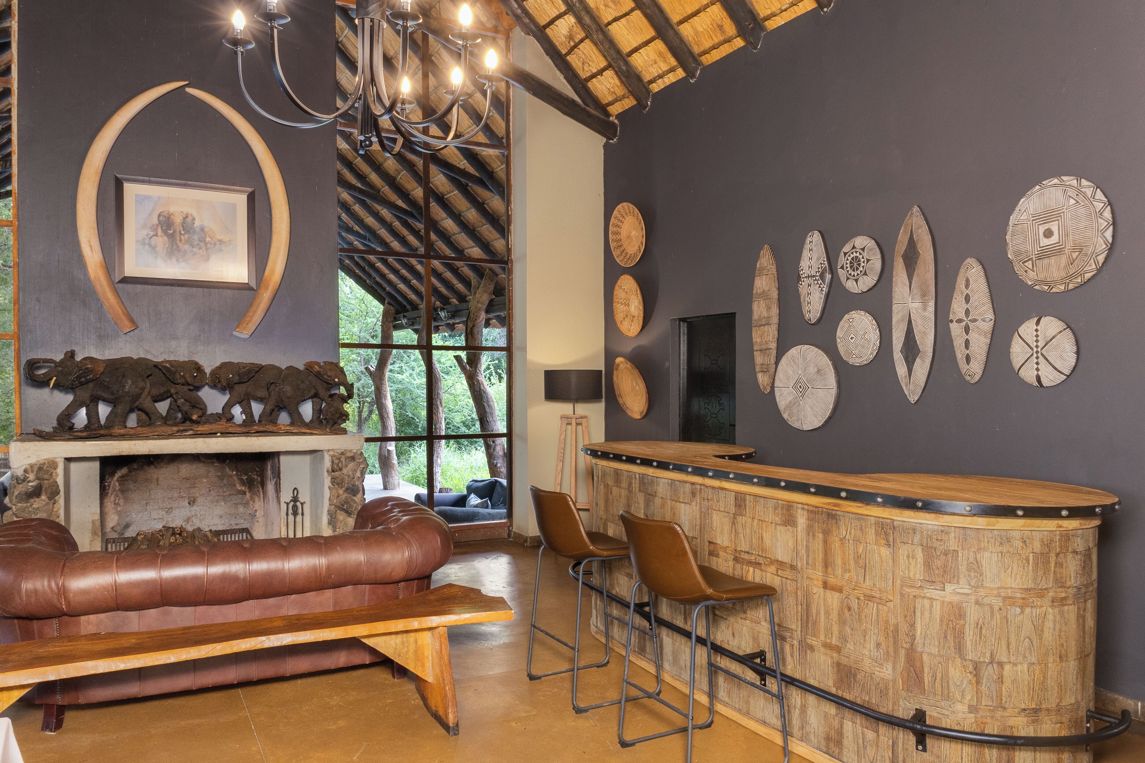 A cozy lounge area with a leather sofa, a wooden bench, and a bar with stools.