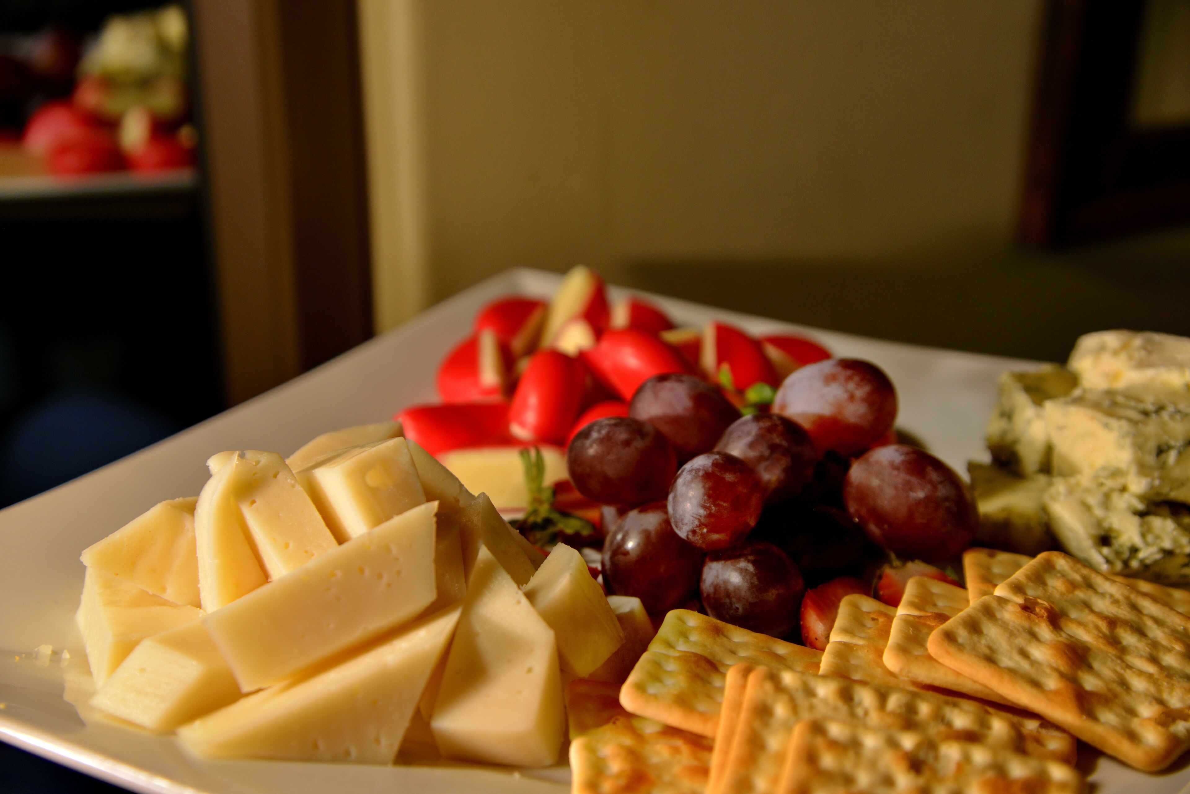 A plate of assorted cheeses, grapes, and crackers.