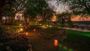 Un chemin de jardin bordé de lanternes, une clôture en bois et un espace aménagé avec une table et des chaises.