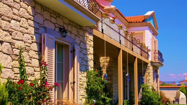 A stone building with a balcony, a garden with flowers, and a clear blue sky. - Yasemin Alacati - Adult Only (Cesme)