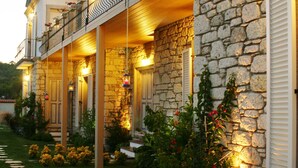 A stone building with a balcony, a garden with stepping stones, and a pathway leading to the entrance. - Yasemin Alacati - Adult Only (Cesme)