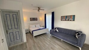 A bedroom with a bed, a gray sofa, a ceiling fan, and a door. - Yasemin Alacati - Adult Only (Cesme)