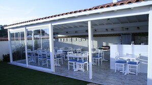A covered patio area with white furniture and a stone wall. - Yasemin Alacati - Adult Only (Cesme)