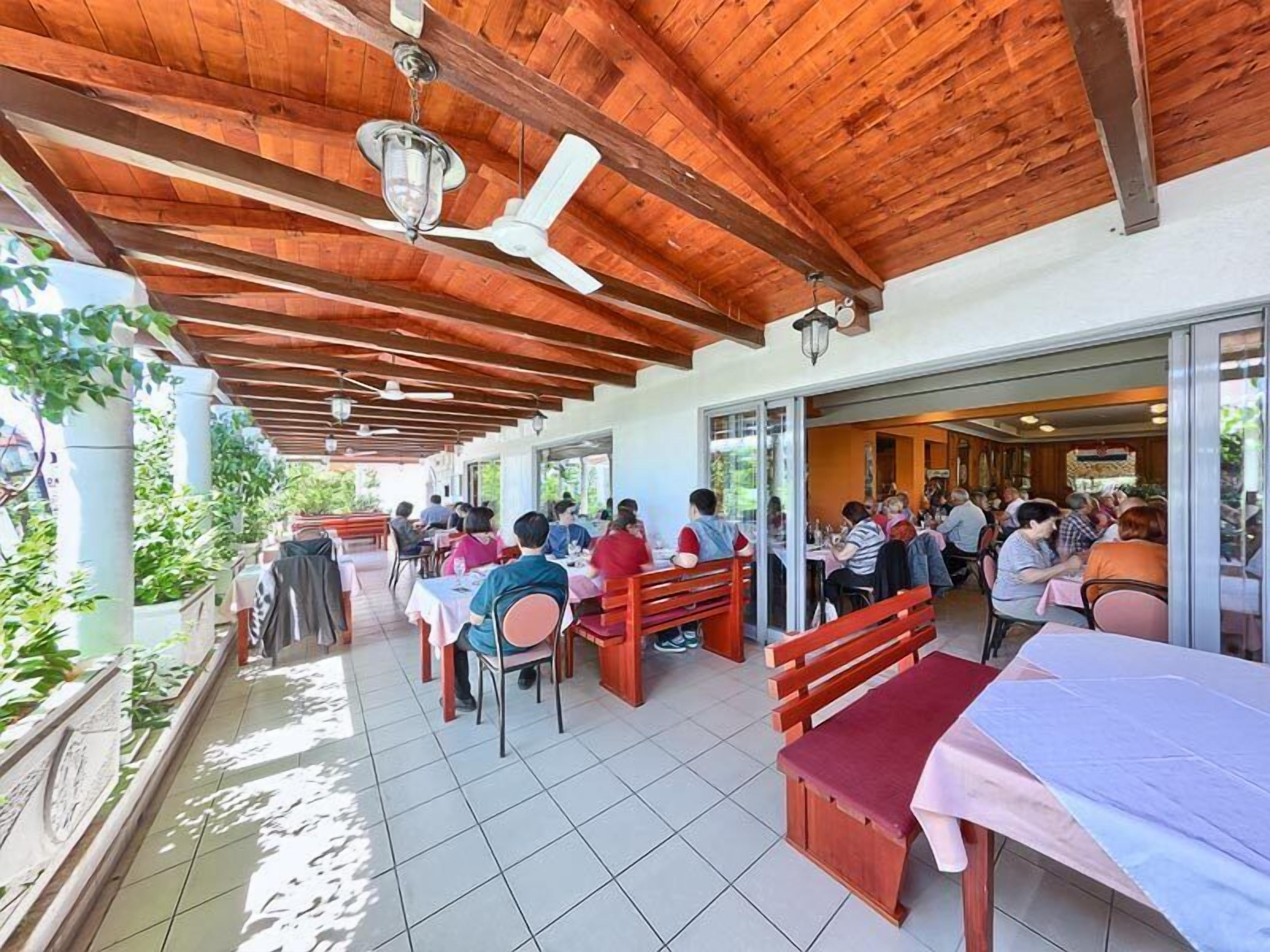 Un espace de restauration en plein air avec des poutres, des tables et des bancs en bois.