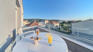 Un balcone con un tavolo apparecchiato per due persone, un bicchiere di succo d'arancia e una piccola ciotola di snack.