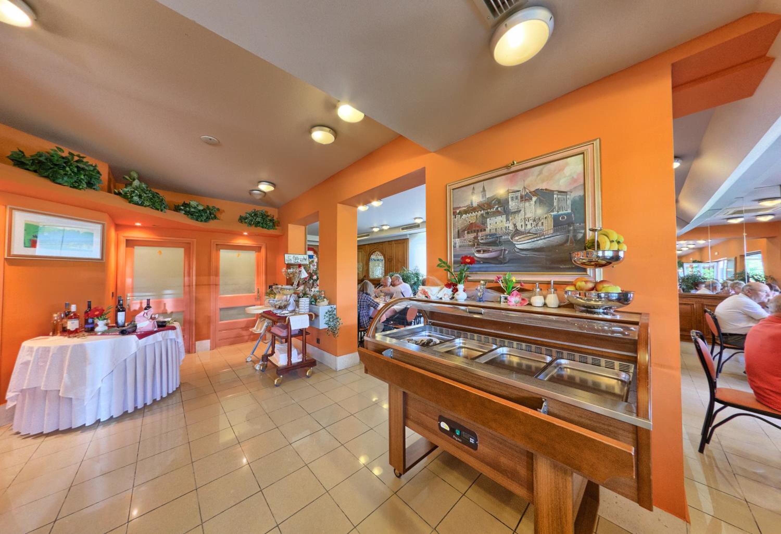 A buffet area with multiple food stations, a table with bottles, and a painting on the wall.
