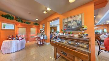 A buffet area with multiple food stations, a table with bottles, and a painting on the wall.