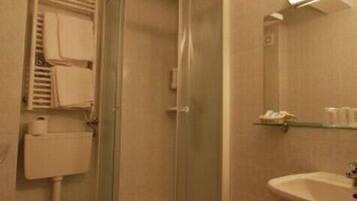 A bathroom with a glass-enclosed shower, a toilet, a sink, and a mirror.