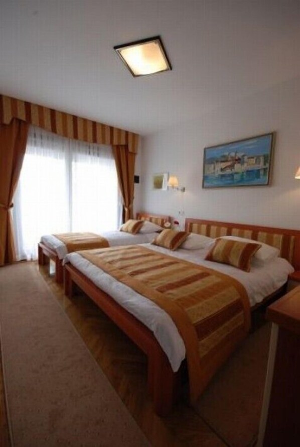 Una habitación de hotel con dos camas, un cuadro en la pared y una ventana con cortinas.