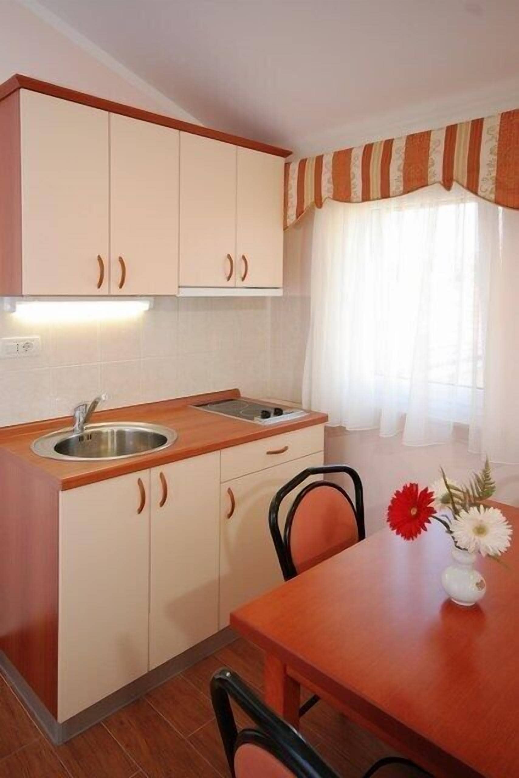 A compact kitchen with wooden cabinets, a sink, and a dining table with chairs.