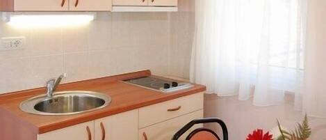 A compact kitchen with wooden cabinets, a sink, and a dining table with chairs.