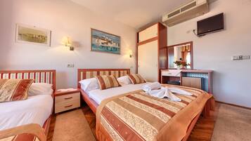 A hotel room with two beds, a desk with a mirror, a flat-screen TV, and artwork on the walls.